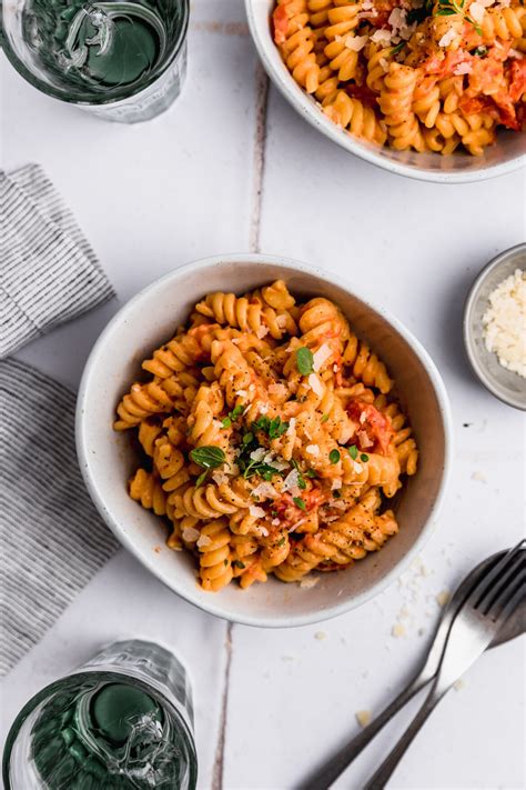 Plato de pasta vegana con salsa cremosa de cebolla y puerro, decorado con hierbas frescas