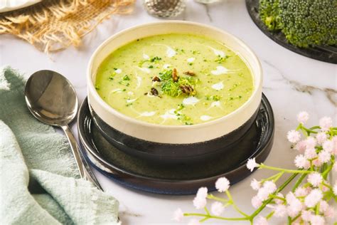 Fotografía de un cuenco humeante de crema de brócoli y espinacas, decorada con chips de kale y semillas