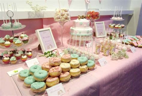 Mesa dulce decorada en tonos pastel con una tarta central y diversos dulces dispuestos armónicamente.