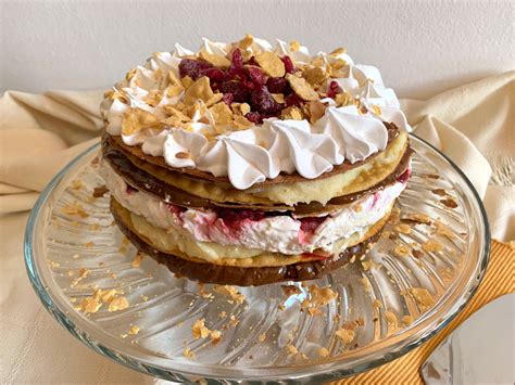 Fotografía de una Torta Amor tradicional con capas de hojarasca, manjar y frambuesas decorada elegantemente.