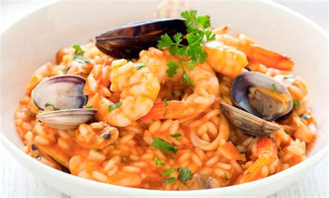 Fotografía de un arroz con mariscos cremoso y bien presentado, con camarones, mejillones y trozos de pimiento.