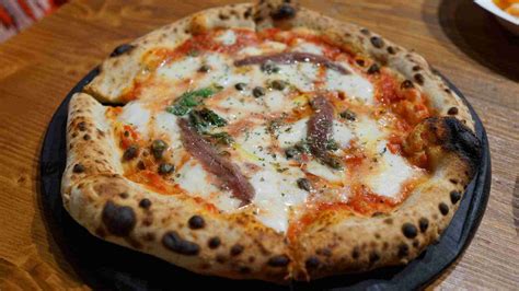 Primer plano de una pizza napolitana con bordes inflados y ligeramente quemados en Cammafa