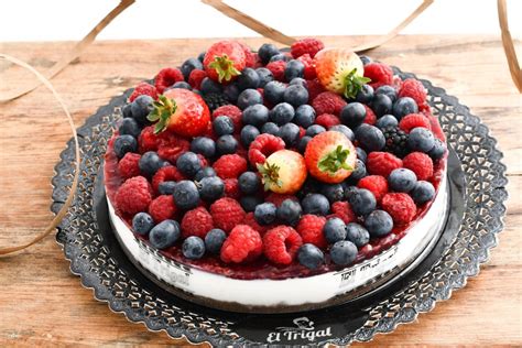 Imagen de una tarta de yogur con frutos rojos decorada con arándanos y frambuesas frescas sobre una base crujiente.