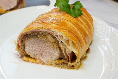 Fotografía profesional de un Solomillo Wellington recién horneado con corte transversal donde se aprecia la carne jugosa y las capas de hojaldre.