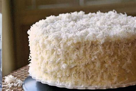 Una torta de coco dorada y esponjosa con glaseado blanco y coco rallado espolvoreado por encima.