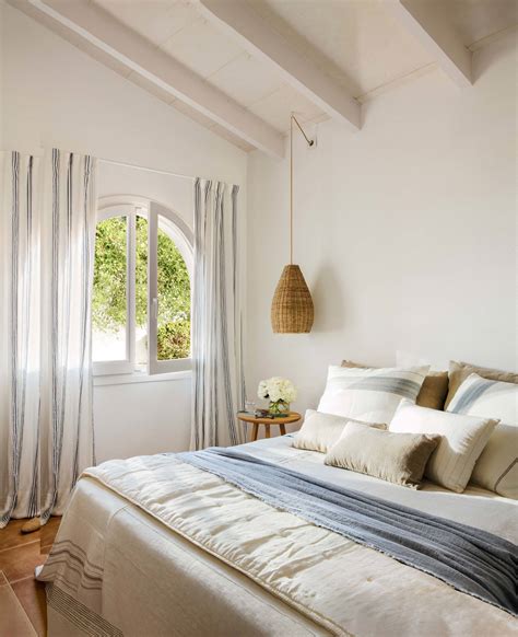 Dormitorio con cama en blanco y detalles decorativos en amarillo mostaza, evocando un estilo nórdico.
