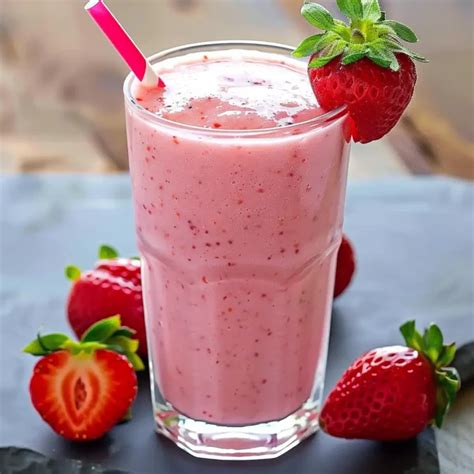 Foto de un smoothie de fresa y yogur recién preparado en un vaso, decorado con una fresa o una hoja de menta