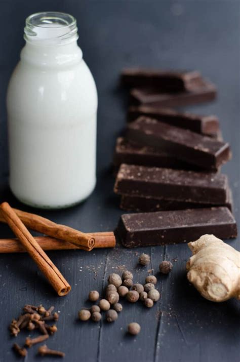 Mesa con ingredientes para chocolate caliente: cacao en polvo, leche, azúcar, chocolate en barra, especias