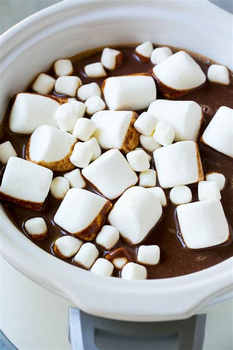 Olla de cocción lenta llena de chocolate caliente con tazas alrededor