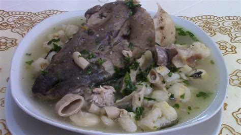 Foto de un plato humeante de caldo de cabeza de cordero servido con hierbas frescas y mote