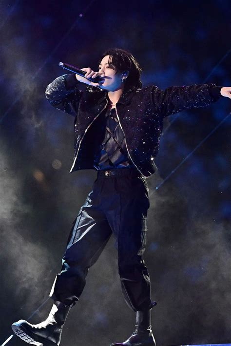 Retrato artístico de Jungkook durante una presentación en vivo con luces escénicas.