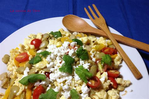 Revoltillo de huevos con habas, tomate y ají, servido con queso y cilantro
