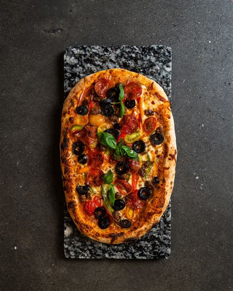 Fotografía gastronómica de una pizza artesanal con ingredientes frescos y masa horneada al estilo italiano