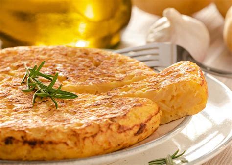 Fotografía gastronómica de una tortilla recién hecha con tomate y cebolla servida en un plato rústico