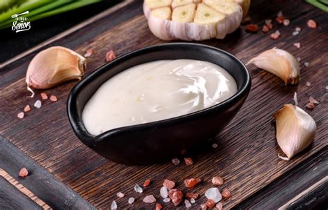 Imagen de un recipiente con salsa de ajo casera cremosa decorada con perejil fresco