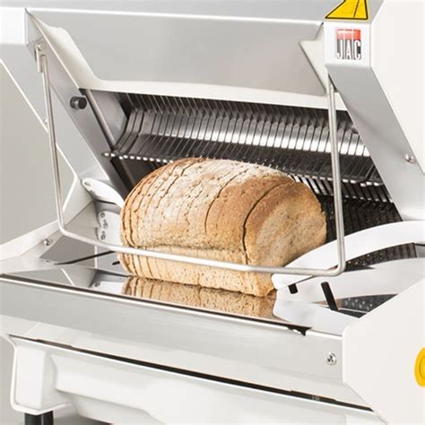 Fotografía detallada de una cortadora de pan profesional operando en una cocina industrial.