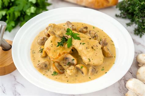 Fotografía gastronómica del plato terminado: fricasé de pollo servido en una cazuela con champiñones y hierbas frescas.