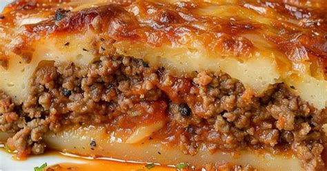 Detalle de un pastel de carne relleno de jamón y queso, con una rodaja mostrando el interior.