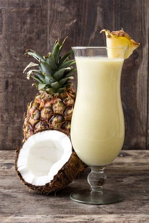 Fotografía profesional de una Piña Colada servida en una copa tipo huracán con decoración tropical