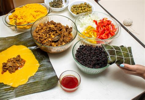 Fotografía de familia preparando hallacas en una mesa grande con diversos ingredientes y hojas de plátano