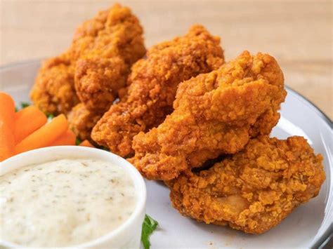Fotografía temática de alitas de pollo crujientes bañadas en salsa picante servidas con apio y aderezo