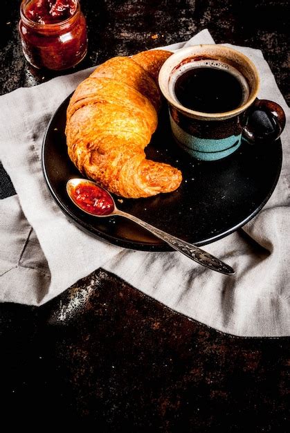 Composición de un desayuno continental con café, cruasanes, mermelada y un pequeño plato de embutidos