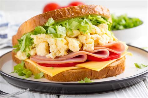 Plato de sándwich con huevo, jamón, queso y tomate cortado por la mitad