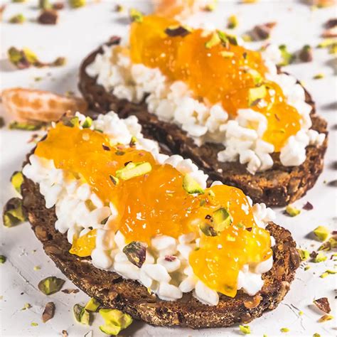 Bodegón elegante con tostadas, queso y un cuenco de mermelada de uva y vino tinto.