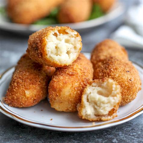 Plato de croquetas de pollo y queso de cabra recién fritas, con una ensalada de acompañamiento.