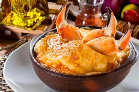 Fotografía gastronómica de un pastel de jaiba servido en fuente de greda con su cubierta gratinada dorada