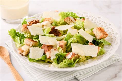 Ilustración o fotografía que represente una ensalada César preparada de forma tradicional en la mesa del comensal.