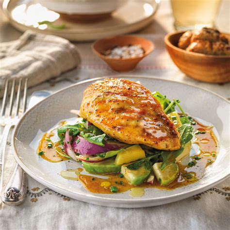 Foto gastronómica de una pechuga de pollo salseada con una reducción brillante de naranja y hierbas frescas.