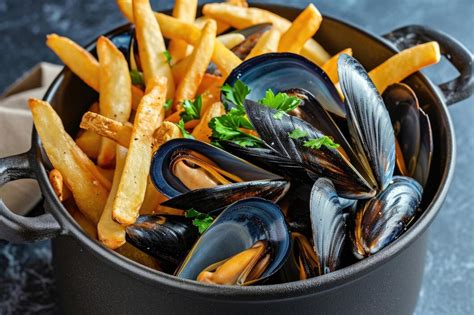Ilustración de un plato de Moules Frites con mejillones al vapor y patatas fritas doradas.