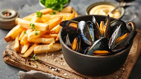Imagen de una cocotte de hierro sirviendo Moules Frites en una mesa.