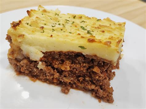 Imagen de un pastel de carne cubierto con puré de patatas cremoso y queso parmesano dorado.