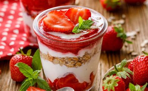 Yogurt cremoso con frutillas y hojas de menta, de apariencia ligera y natural.