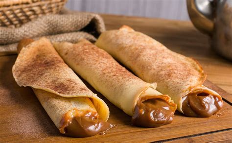 Foto de panqueques enrollados con manjar y espolvoreados con azúcar flor.