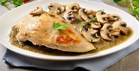 Fotografía profesional de una pechuga de pollo dorada servida con una cremosa salsa de champiñones sobre un fondo elegante.