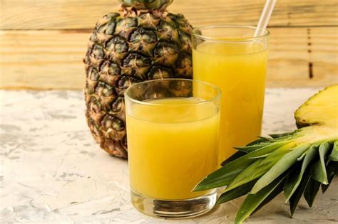 Piña fresca y jugo de piña en un vaso al lado de un bizcocho recién horneado.