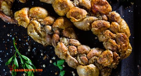 Fotografía gastronómica de chunchules de cordero a la parrilla servidos con rodajas de limón y hierbas frescas.