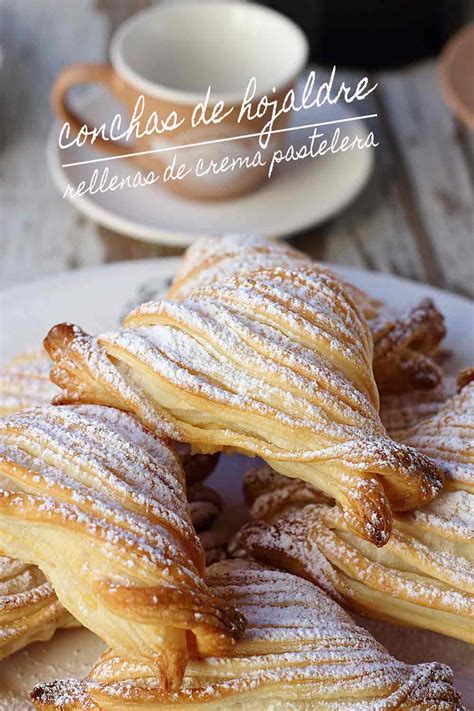 Foto detallada de caracolas de hojaldre doradas y rellenas de crema pastelera con un toque de azúcar glass