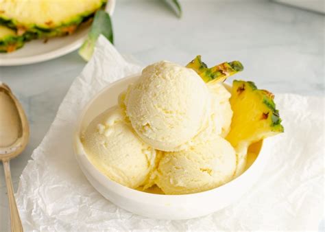 Imagen de un helado de piña artesanal servido en una copa decorado con trozos de fruta fresca