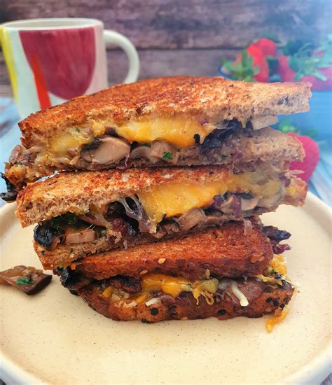 Primer plano de un sándwich grilled cheese con cebolla caramelizada fundiéndose