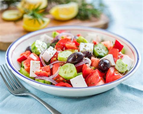 Infografía que muestra los ingredientes tradicionales de la ensalada griega: tomate, pepino, cebolla roja, aceitunas Kalamata y queso feta