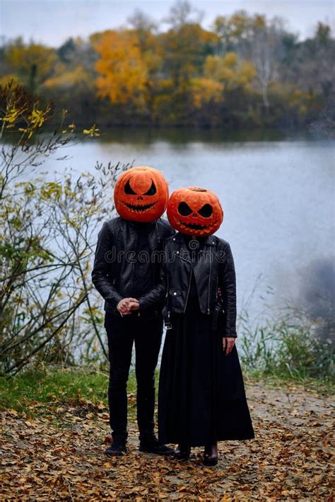 Pareja disfrazada de brujas y vampiros con calabazas en la cabeza
