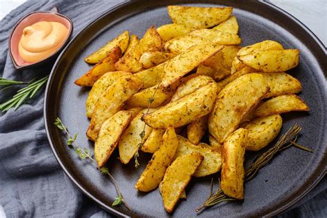 Plato de papas al horno doradas y crujientes, adornadas con hierbas frescas.