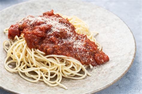 Plato de pasta con abundante salsa ragú y queso rallado.