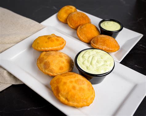 Ilustración de varios pastelitos venezolanos con diferentes salsas al lado