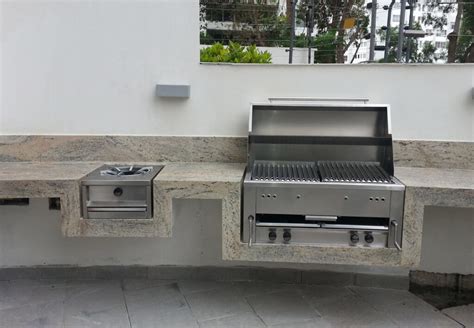 Fotografía profesional de una parrilla empotrada de acero inoxidable de 4 quemadores instalada en una terraza moderna.