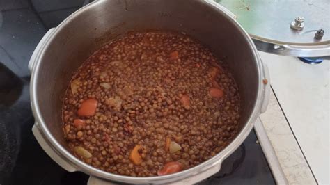 fotografía de una olla con lentejas cocinándose a fuego lento, con la tapa entreabierta